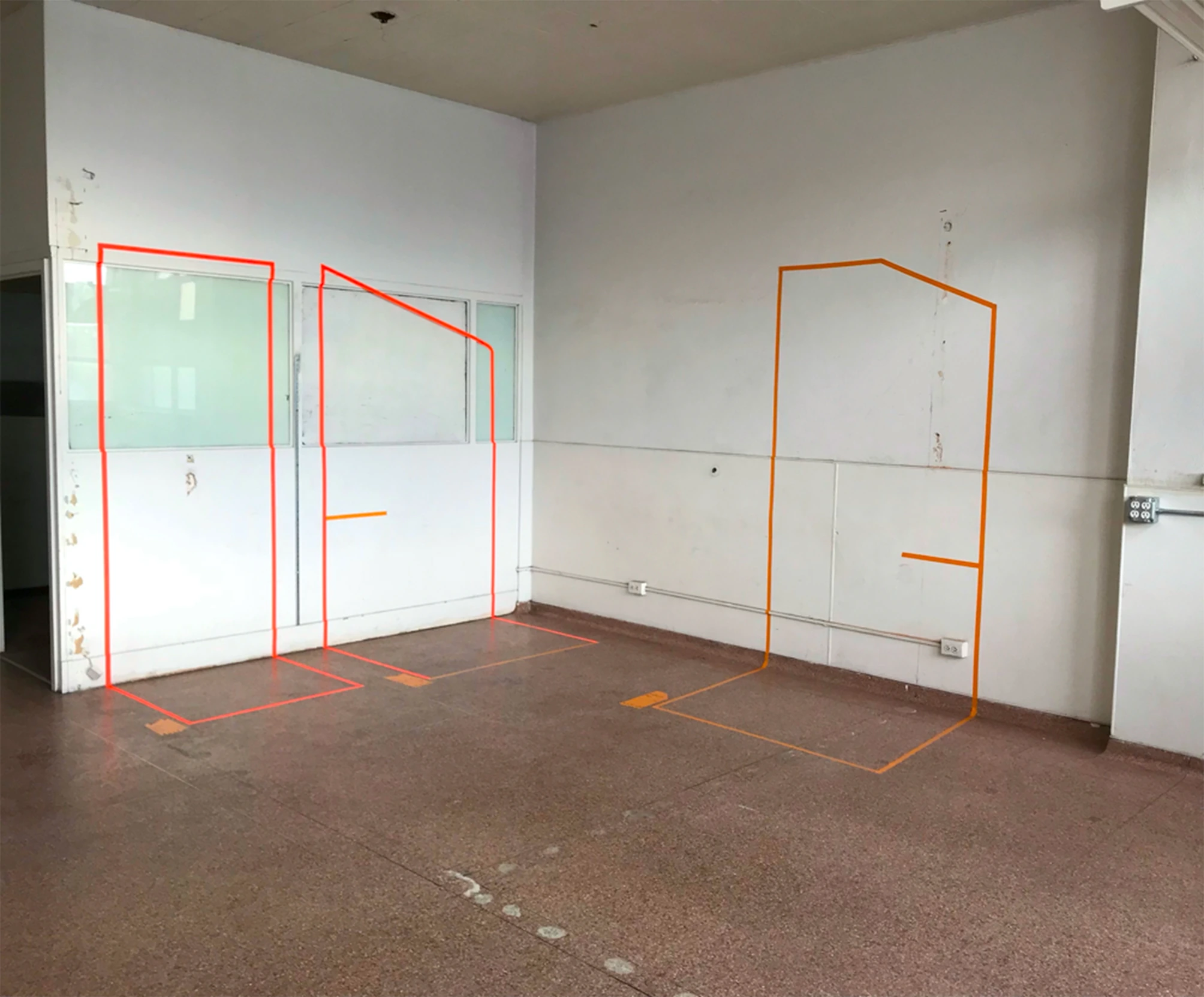 Booth elevations taped out on a wall in orange tape